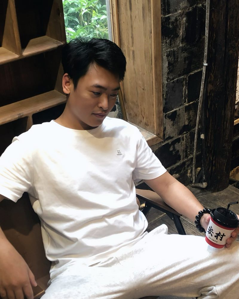 朱明君坐在木屋里，手里拿着一杯咖啡